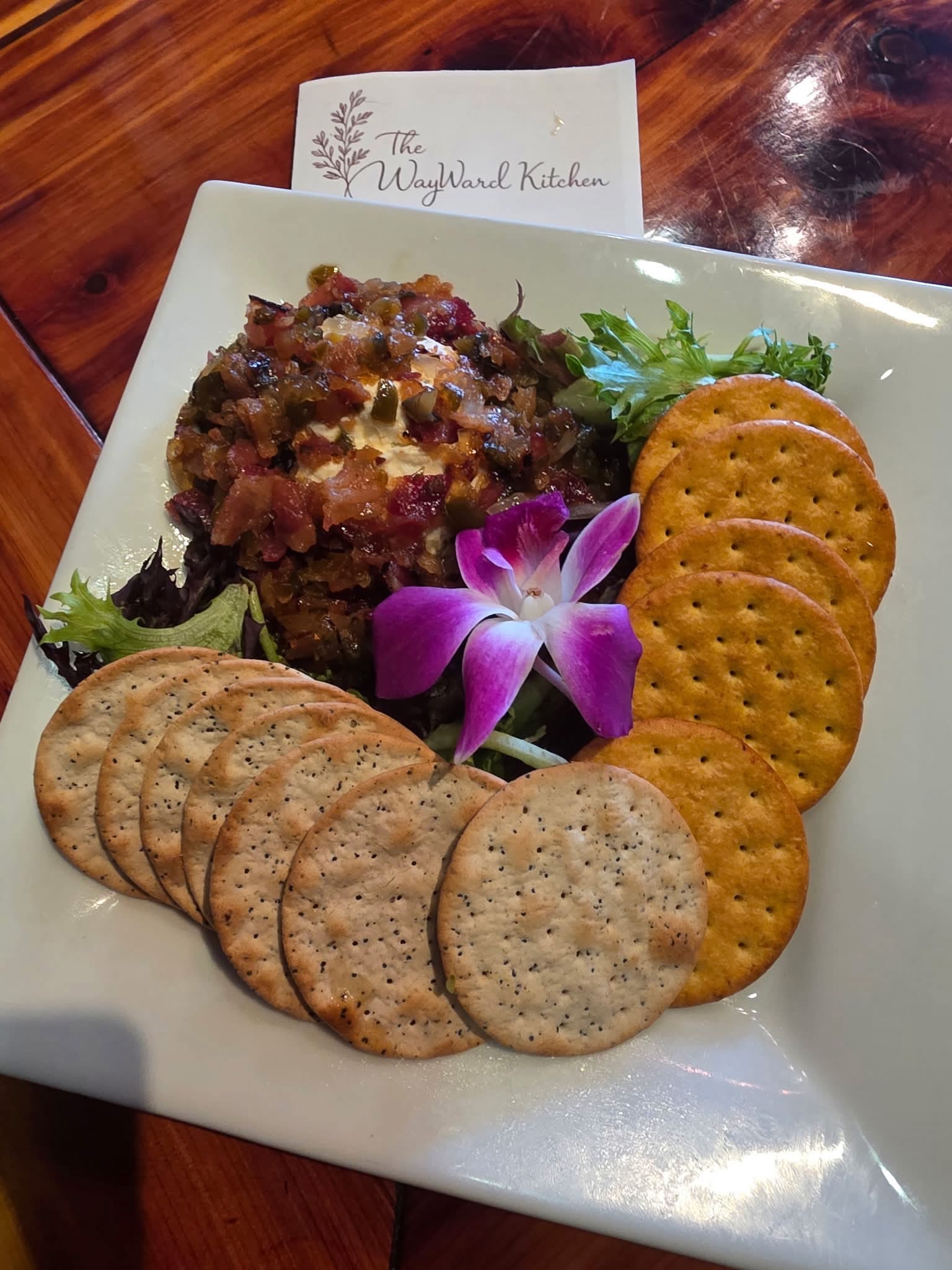 Savory appetizer served with crackers and a purple orchid